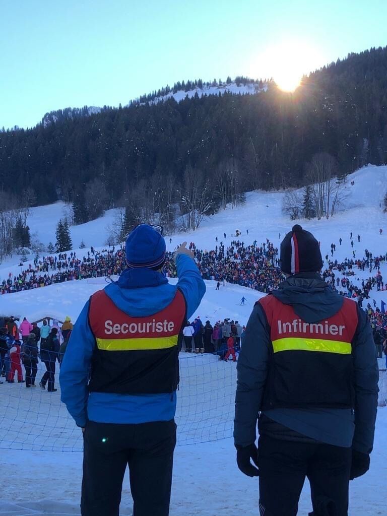 Un secouriste en tenue et un infirmier en uniforme observent attentivement le public lors d’un événement, prêts à intervenir en cas de besoin pour assurer la sécurité et gérer les urgences.